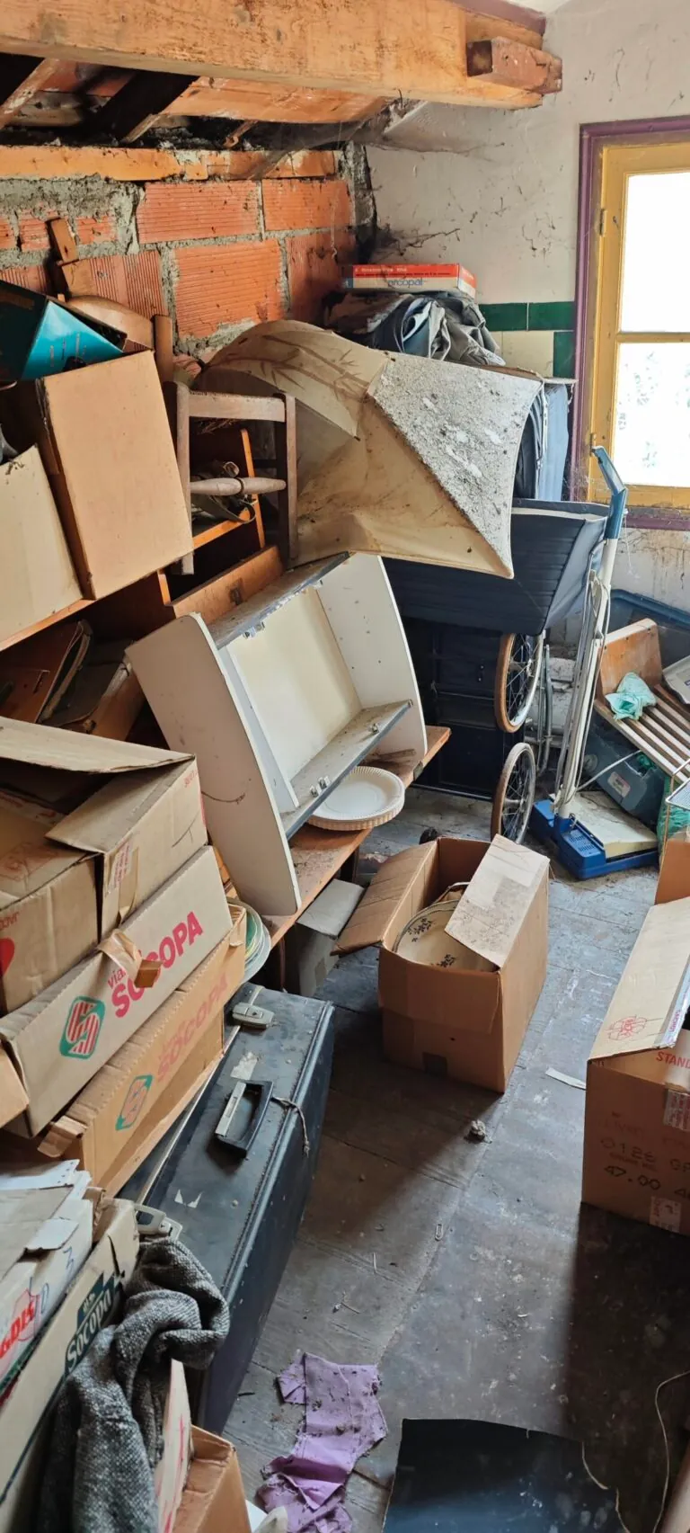 Mobilier et encombrants devant un mur en briques avant intervention